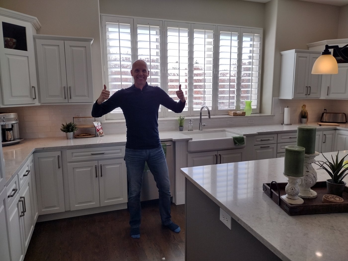 Happy client giving a thumbs-up in a refinished white kitchen