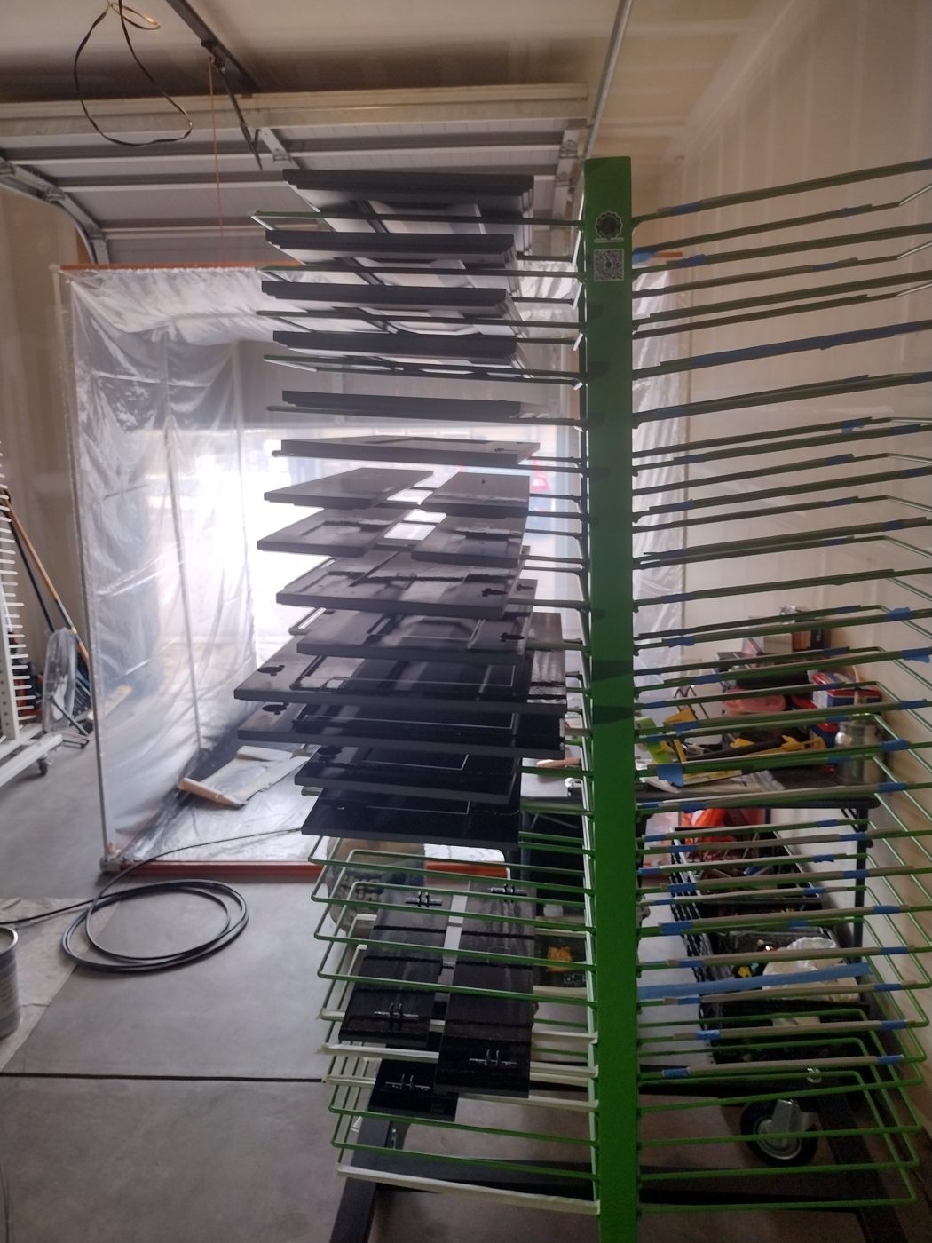Drying rack loaded with freshly sprayed black cabinet doors in the Rock's Finest Finishes spray booth