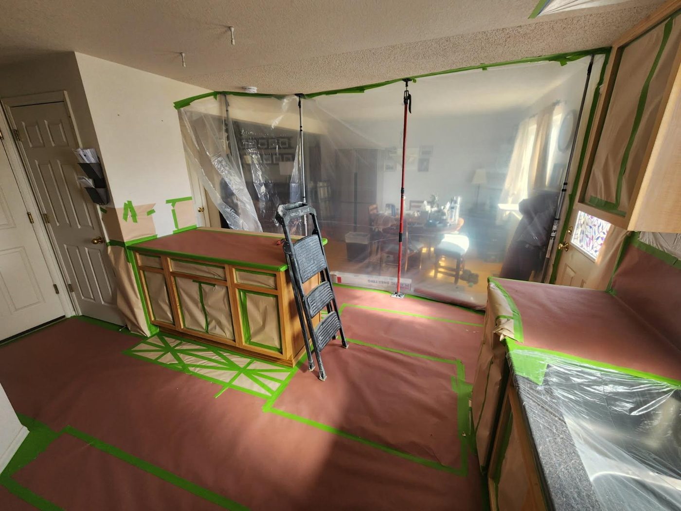Kitchen fully masked with plastic zip walls, paper and tape before cabinet refinishing