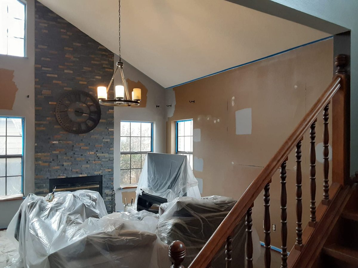 Living room prepped with patched walls, plastic sheeting and tape by Rock's Finest Finishes