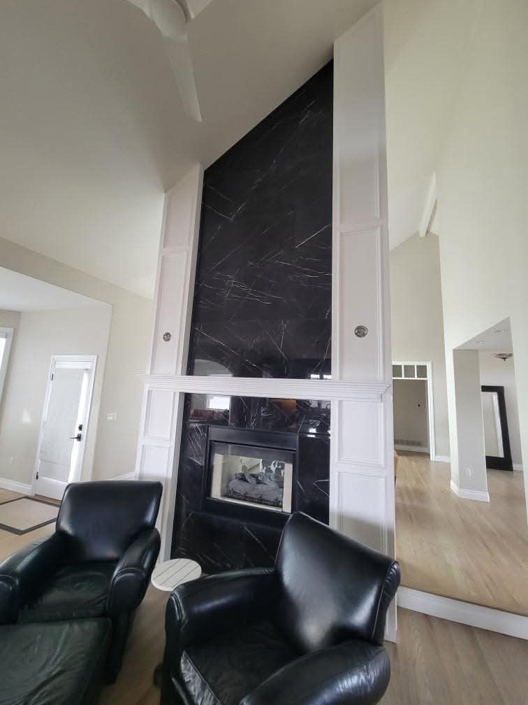 Black marble fireplace with white paneled surround painted by Rock's Finest Finishes